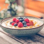 A bowl of porridge topped with fresh mixed berries like blueberries, raspberries, and strawberries.